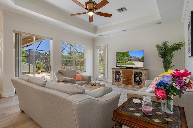 27318 Sora Blvd, Wesley Chapel, FL 33544 - living area with baseboards, light wood-type flooring, crown molding, a tray ceiling, and ceiling fan