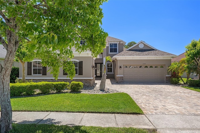 27318 Sora Blvd, Wesley Chapel, FL 33544 - view of front facade featuring stucco siding, stone siding, a front lawn, an attached garage, and driveway