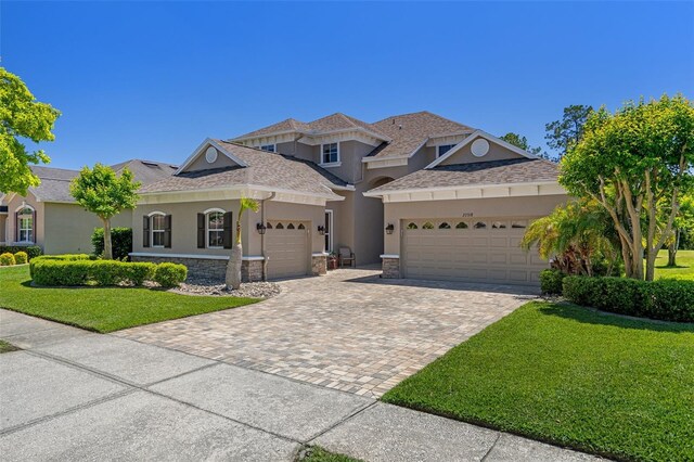 27318 Sora Blvd, Wesley Chapel, FL 33544 - view of front of house featuring a front lawn, decorative driveway, a garage, and stucco siding