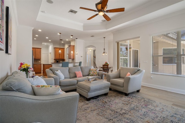 27318 Sora Blvd, Wesley Chapel, FL 33544 - living room with crown molding, a wealth of natural light, a tray ceiling, a ceiling fan, and visible vents