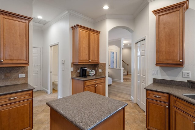 27318 Sora Blvd, Wesley Chapel, FL 33544 - kitchen with backsplash, brown cabinetry, dark countertops, and arched walkways