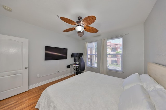 bedroom with light wood-style flooring, ceiling fan, and baseboards