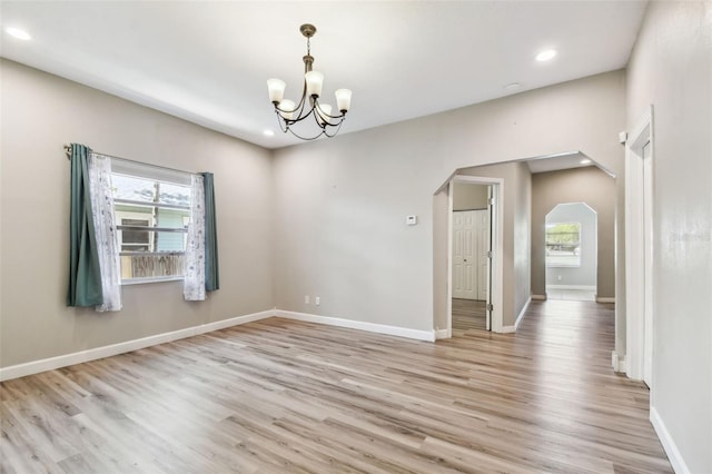 unfurnished room with recessed lighting, arched walkways, light wood finished floors, and a wealth of natural light