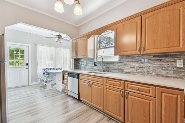 kitchen with stainless steel dishwasher, a sink, tasteful backsplash, light wood-type flooring, and light countertops