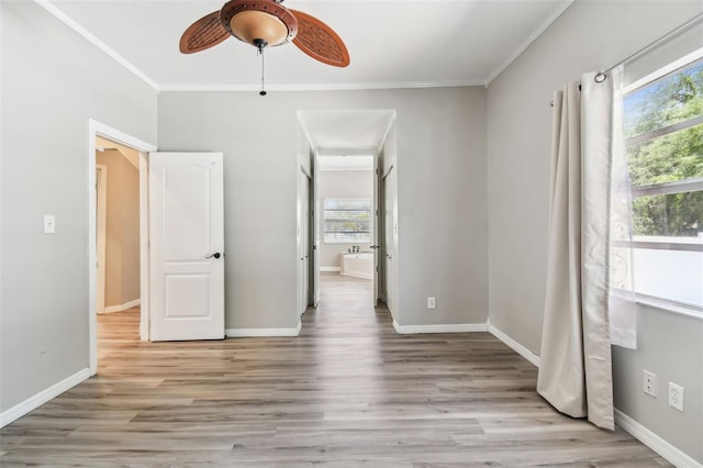 unfurnished bedroom with crown molding, multiple windows, and light wood-style floors