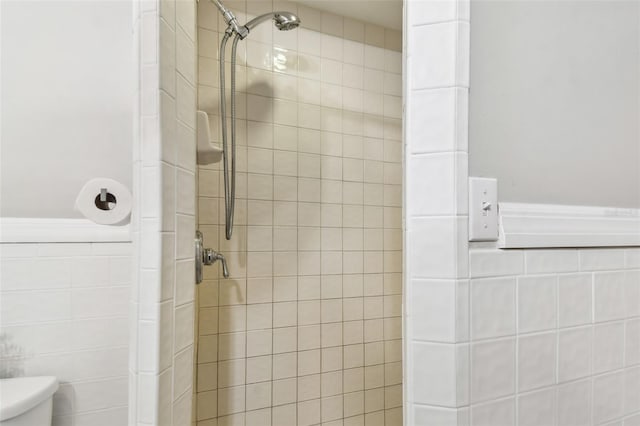 full bath with toilet, tile walls, and a stall shower