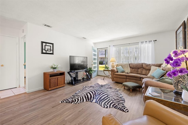 living area featuring a textured ceiling, wood finished floors, and visible vents