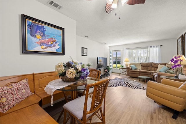 living area featuring ceiling fan, wood finished floors, and visible vents