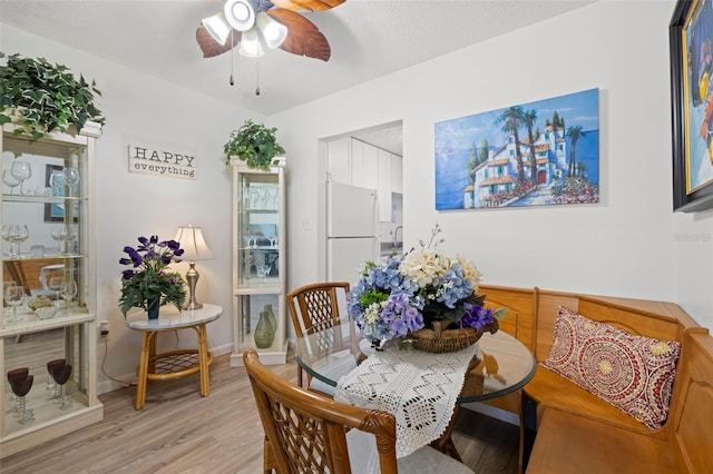 dining space featuring ceiling fan, baseboards, and light wood-style flooring