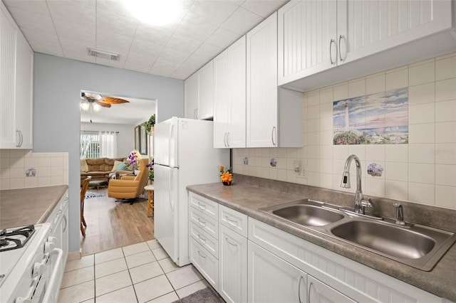 kitchen featuring a sink, white appliances, light tile patterned floors, white cabinets, and visible vents