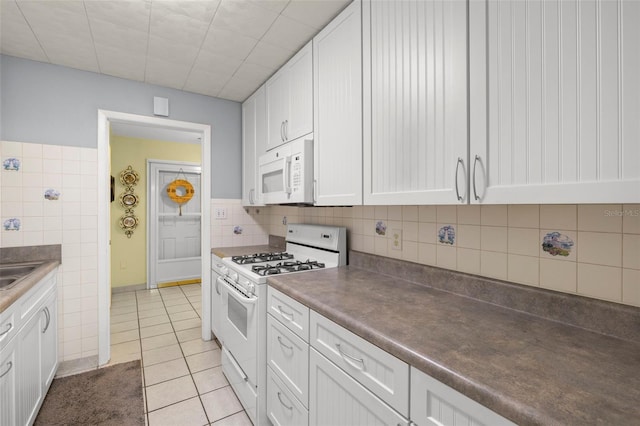 kitchen featuring white cabinets, dark countertops, white appliances, light tile patterned flooring, and decorative backsplash