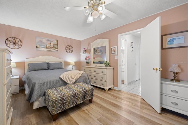 bedroom with ceiling fan, ensuite bath, and light wood-type flooring