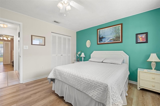 bedroom with baseboards, wood finished floors, visible vents, and a closet