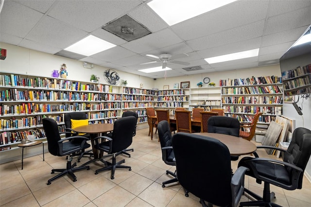 office with ceiling fan, a drop ceiling, bookshelves, and tile patterned floors