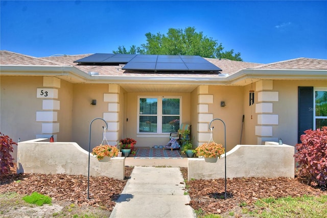 53 Paine Dr, Winter Haven, FL 33884 - property entrance featuring stucco siding, a shingled roof, and solar panels