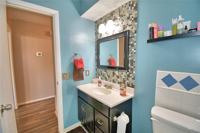 53 Paine Dr, Winter Haven, FL 33884 - bathroom featuring wood finished floors, toilet, vanity, baseboards, and decorative backsplash