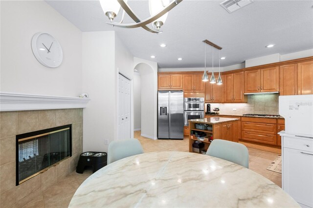 17206 Emerald Chase Dr, Tampa, FL 33647 - kitchen with brown cabinetry, visible vents, light stone countertops, an inviting chandelier, and stainless steel appliances