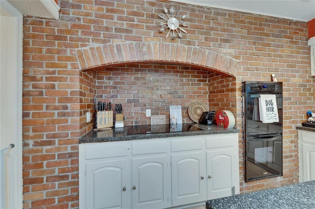 1603 Cottagewood Dr, Brandon, FL 33510 - kitchen with white cabinets, brick wall, dark stone countertops, and dobule oven black
