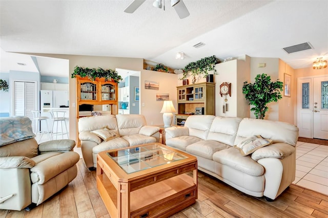 living area featuring visible vents, a ceiling fan, light wood-style flooring, and vaulted ceiling