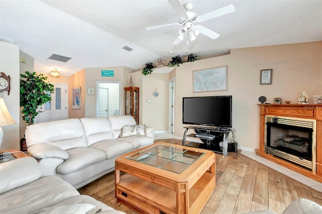 living area with light wood-style flooring, a fireplace, baseboards, a ceiling fan, and lofted ceiling