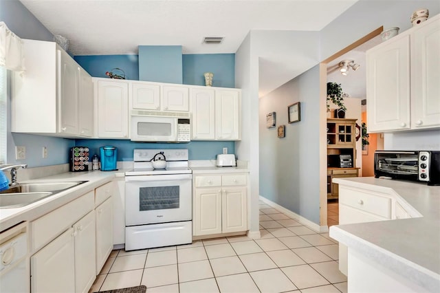 kitchen with a sink, visible vents, a toaster, light tile patterned flooring, and white appliances