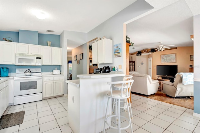kitchen featuring open floor plan, white appliances, light tile patterned floors, and white cabinets