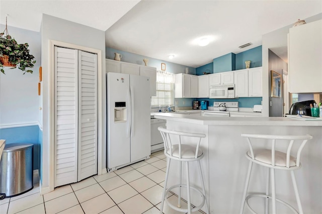 kitchen featuring white appliances, light countertops, a sink, a peninsula, and a kitchen breakfast bar