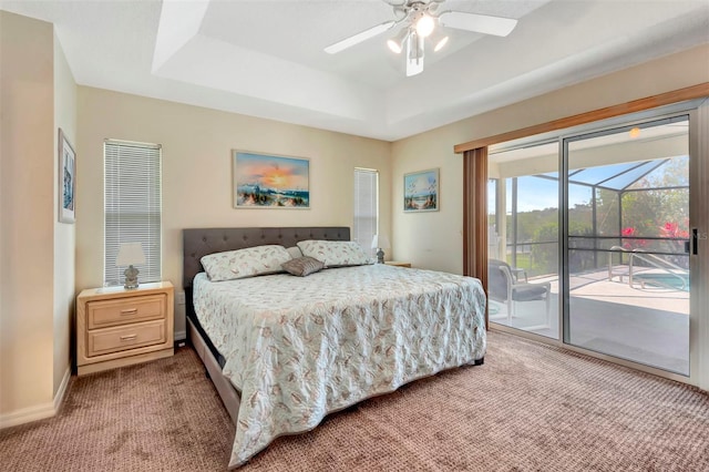 carpeted bedroom featuring a raised ceiling, ceiling fan, and access to exterior