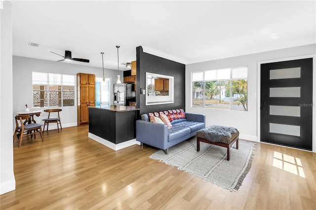 living room featuring visible vents, light wood-type flooring, and baseboards