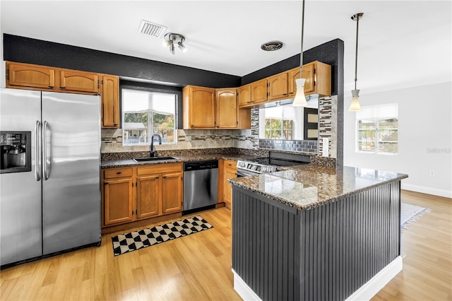 kitchen featuring light wood-style flooring, a sink, appliances with stainless steel finishes, visible vents, and a peninsula
