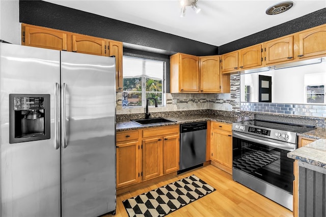 kitchen featuring decorative backsplash, a sink, appliances with stainless steel finishes, light wood-style floors, and visible vents