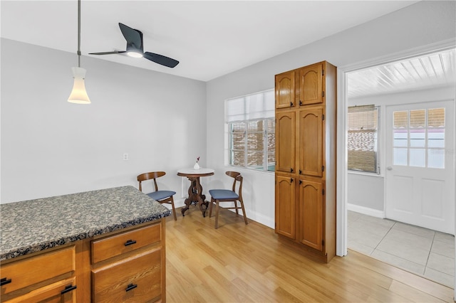 kitchen featuring ceiling fan, a healthy amount of sunlight, brown cabinetry, and light wood-style floors