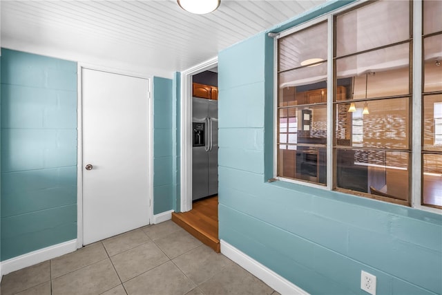 hallway featuring light tile patterned floors and baseboards