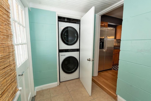 laundry room featuring light tile patterned floors, stacked washer / drying machine, and laundry area