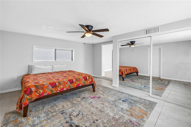bedroom featuring a textured ceiling, visible vents, ceiling fan, and tile patterned floors