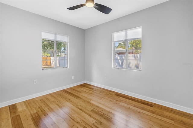 empty room with baseboards, a ceiling fan, a wealth of natural light, and hardwood / wood-style floors