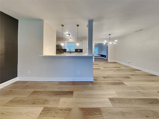 kitchen with light wood-type flooring, an inviting chandelier, and hanging light fixtures