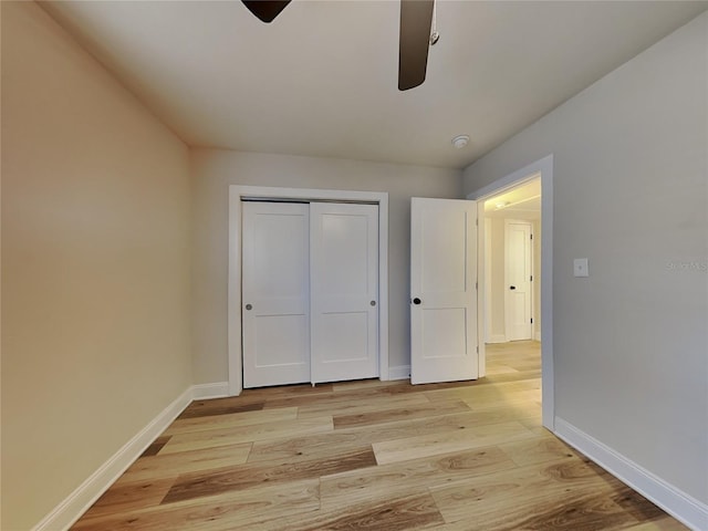 unfurnished bedroom featuring light wood-type flooring, a closet, ceiling fan, and baseboards