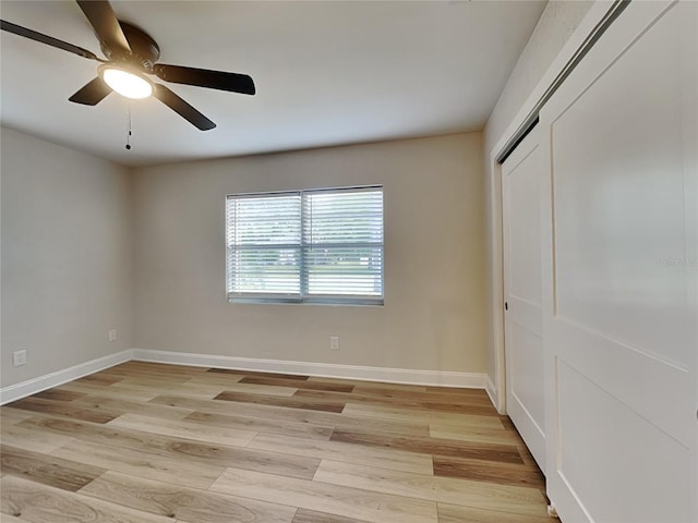 unfurnished bedroom featuring ceiling fan, a closet, light wood finished floors, and baseboards
