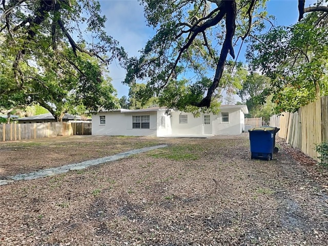 rear view of property featuring a fenced backyard and stucco siding