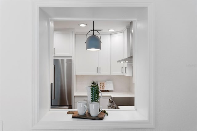 interior space featuring light countertops, freestanding refrigerator, pendant lighting, range, and white cabinetry