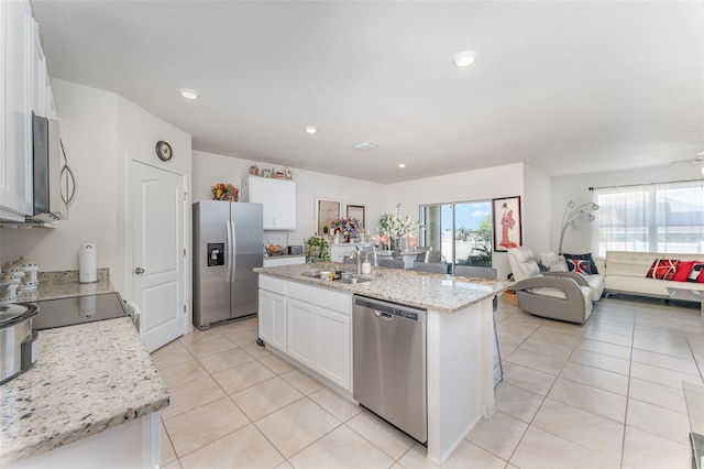 947 Serchio St, Haines City, FL 33844 - kitchen with light tile patterned floors, appliances with stainless steel finishes, a sink, open floor plan, and a center island with sink