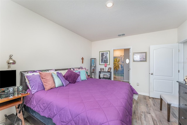 947 Serchio St, Haines City, FL 33844 - bedroom featuring visible vents, baseboards, connected bathroom, and wood finished floors