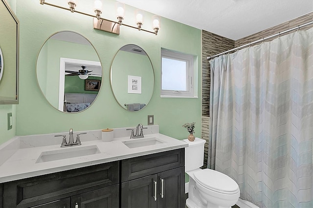 bathroom with double vanity, toilet, ceiling fan, and a sink