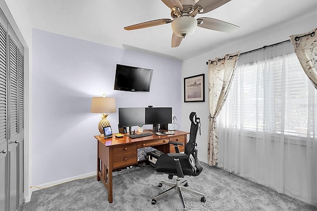 carpeted office space featuring baseboards and ceiling fan