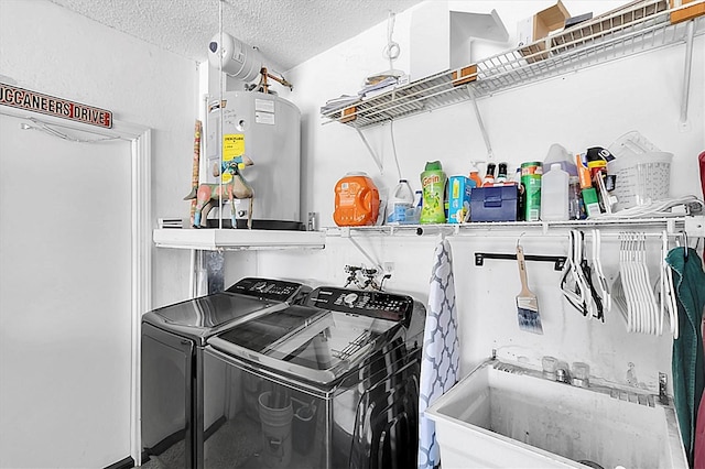 washroom featuring a textured ceiling, washer and dryer, a sink, electric water heater, and laundry area