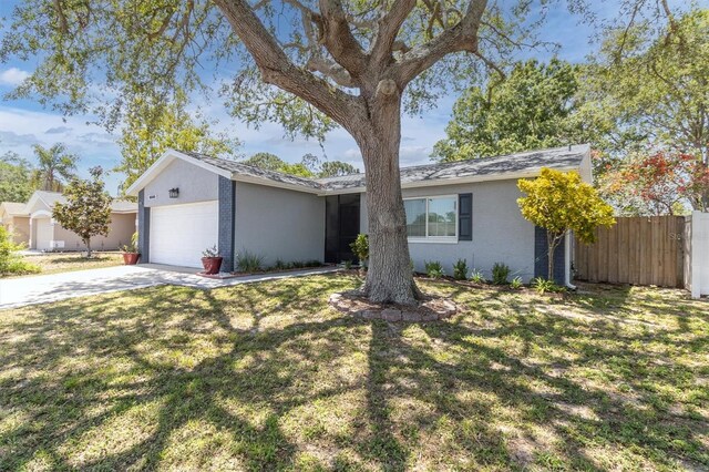 ranch-style home featuring a front yard, fence, an attached garage, and driveway