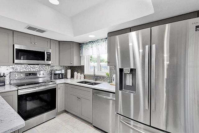 kitchen with gray cabinetry, light tile patterned floors, visible vents, a sink, and appliances with stainless steel finishes
