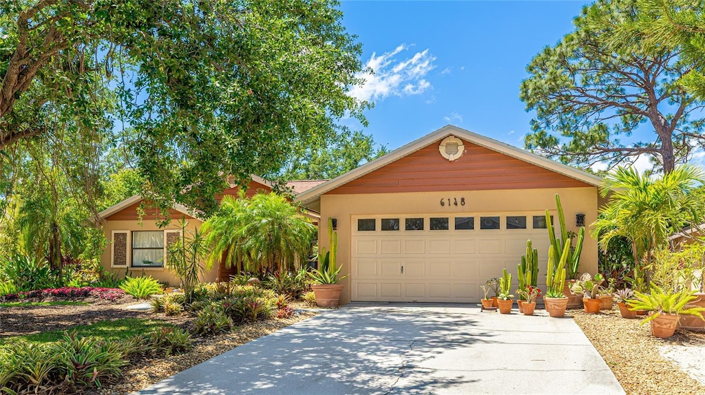 ranch-style house with concrete driveway, an attached garage, and stucco siding