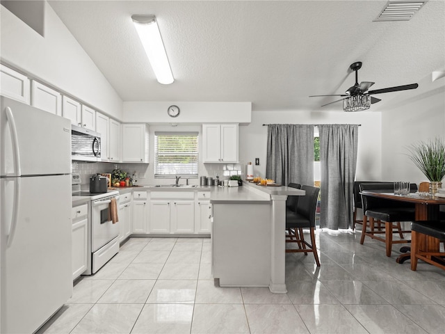 30 N Kaufman Ter, Inverness, FL 34453 - kitchen featuring white cabinets, a breakfast bar, white appliances, backsplash, and visible vents